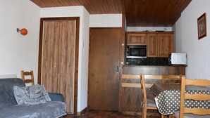 A compact living space with a kitchenette, a sofa, and a dining table.