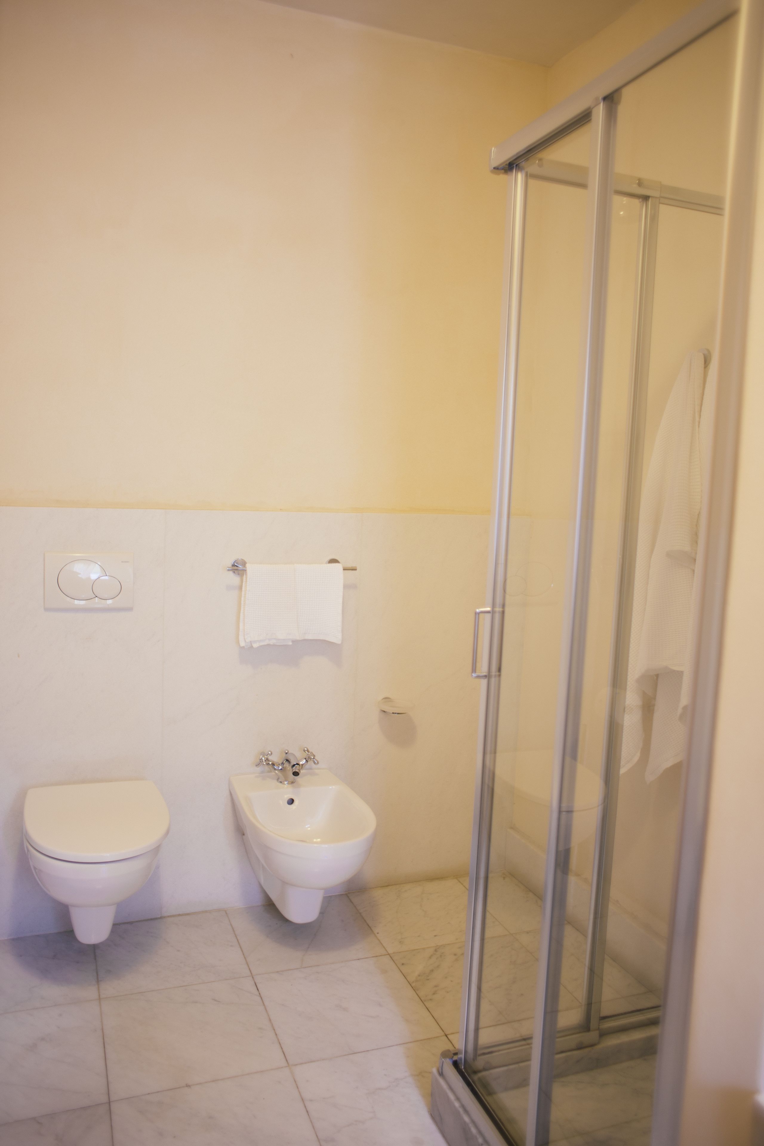 Een badkamer met toilet, bidet en een douchecabine met glazen wanden.