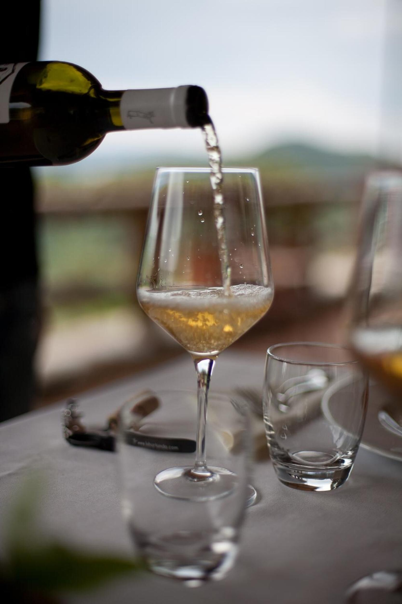 Ein Weinfass wird in ein Glas auf einem Tisch mit Blick auf die Landschaft eingeschenkt.