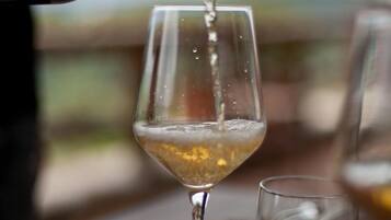 Ein Weinfass wird in ein Glas auf einem Tisch mit Blick auf die Landschaft eingeschenkt.