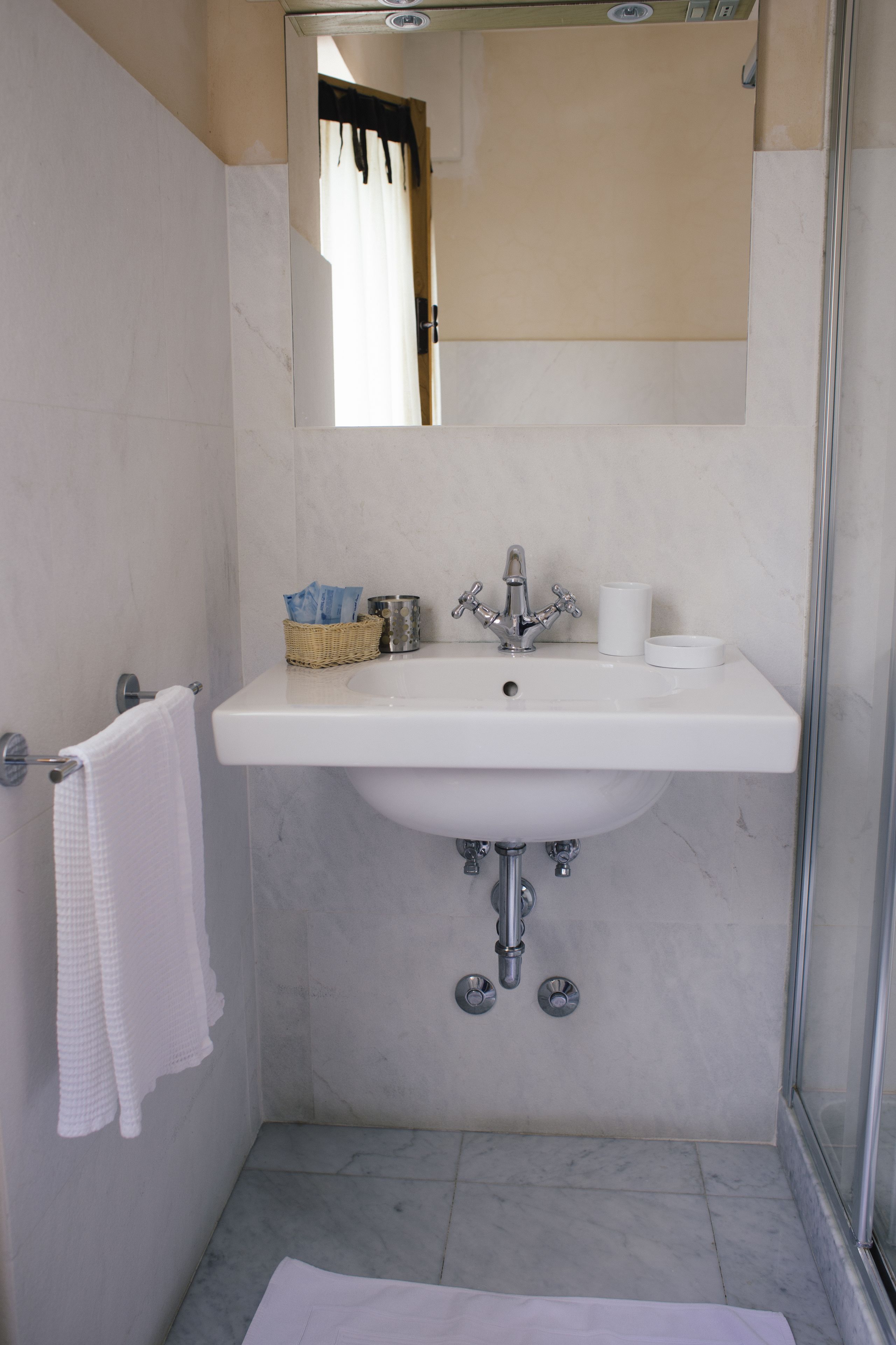 A bathroom with a white sink, a mirror, a towel rack, and a shower area.