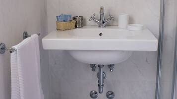 A bathroom with a white sink, a mirror, a towel rack, and a shower area.