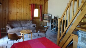 A wooden interior with a sofa, a TV, a table, and a staircase. - Comfortable 4-room duplex, 6 pers, garage, Pralognan-la-Vanoise (Pralognan-la-Vanoise)