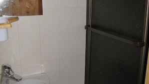 A bathroom with white tiles, a wooden shelf, a white toilet, and a black door. - Cozy studio near shops, south balcony (Pralognan-la-Vanoise)