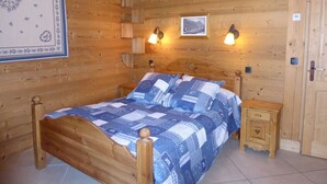 A wooden cabin bedroom with a bed, two bedside tables, and wall-mounted lamps.