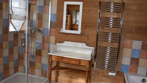 A bathroom with a shower, a sink, a mirror, and a towel rack.