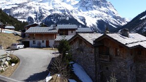 Ein Chalet-Stil Gebäude mit Natursteinfassade und Holzdach, eingebettet in eine verschneite Landschaft mit Bergen.