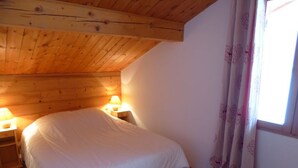 Ein Schlafzimmer mit Holzboden, einem Einzelbett, zwei Nachttischlampen und einem fenster mit Vorhängen.