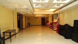 A spacious hallway with a bench, a trash bin, and a wall-mounted television. - Hotel Anantha Executive Suites (Mumbai)
