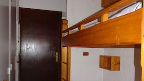 Ein Schlafraum mit Etagenbetten, einer Holztür und einem kleinen Holzschrank.