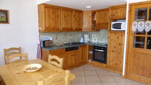 A kitchen with wooden cabinets, a microwave, a toaster, and a coffee maker. - Comfortable T3 with large balcony - Pets allowed (Pralognan-la-Vanoise)