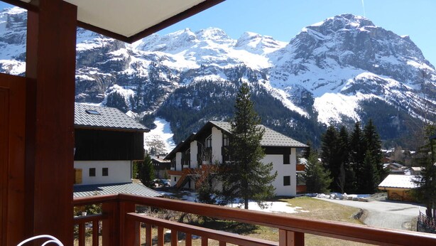 A balcony with a view of snow-covered mountains and a chalet-style building. - Comfortable T3 with large balcony - Pets allowed (Pralognan-la-Vanoise)