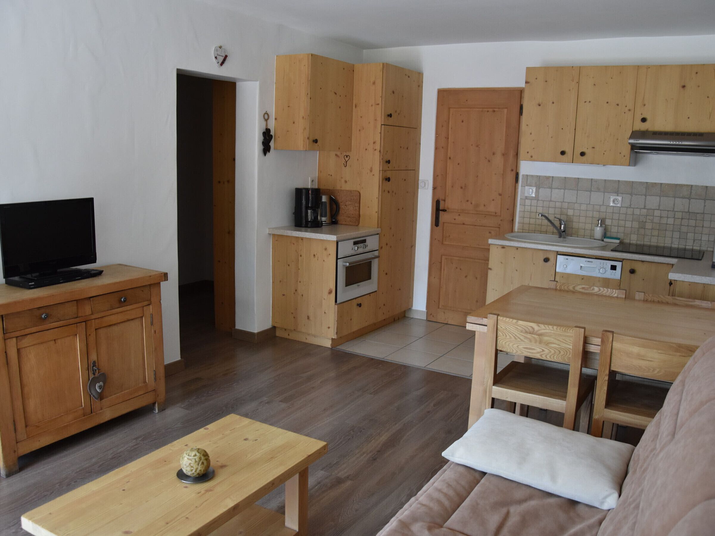 Een kleine keuken met houten kastjes, een inbouwoven, een koffiezetapparaat en een gootsteen.