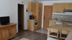 Cocina compacta con armarios de madera, horno empotrado, cafetera y lavamanos.