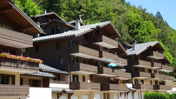 A row of traditional chalet-style buildings with balconies, set against a backdrop of lush green hills. - Cozy apartment with south balcony in Bozel (Bozel)