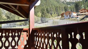 A mountain view from a wooden balcony with a decorative fence.