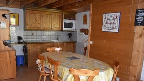 A cozy kitchen with wooden cabinets, a tiled backsplash, and a dining table with chairs.