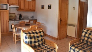 A cozy kitchen with wooden cabinets, a dining table, and plaid chairs.