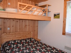 Un lit superposé avec une tête de lit en bois et une couvre-lit matelassée.