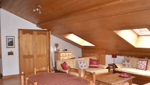 A cozy attic room with wooden furniture, a dining table, and a sofa. - Spacious duplex for 6 with balcony in the Alps (Pralognan-la-Vanoise)