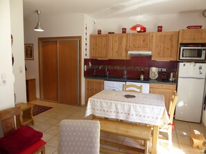 Una cocina compacta con armarios de madera, un microondas y un refrigerador.