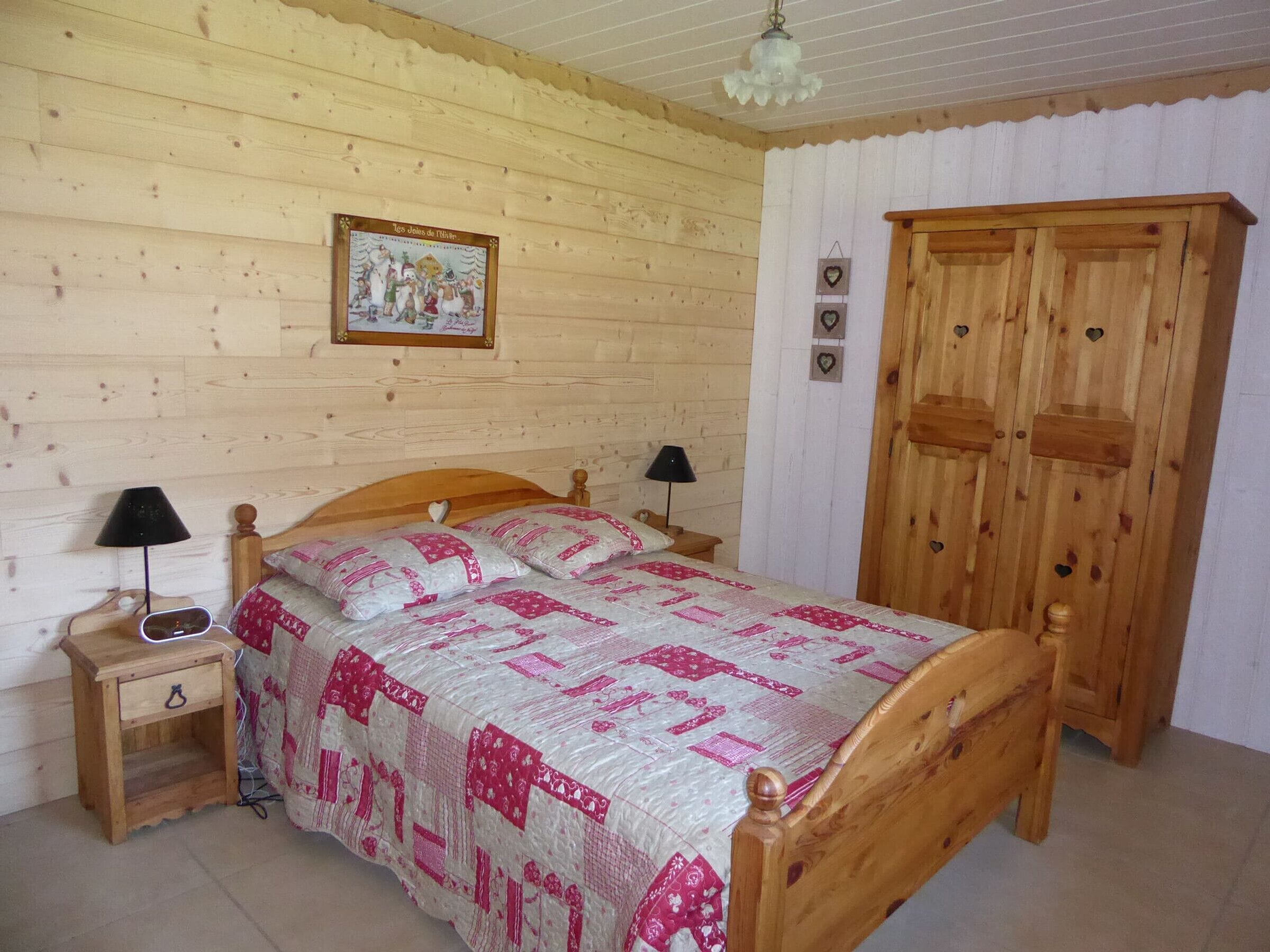 Ein Schlafzimmer aus Holz mit Bett, Nachttischen, einem Kleiderschrank und einem Wandbild.