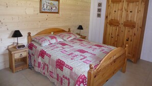 Een houten slaapkamer met een bed, nachtkastjes, een kledingkast en een aan de muur hangend schilderij.