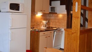 A compact kitchen with white appliances, wooden cabinets, and a tiled backsplash. - Duplex T4 for 7 with terrace and parking in Esquièze-Sère (Esquièze-Sère)