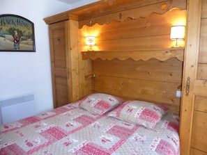 A wooden bed with a quilted headboard and two wall-mounted lamps.