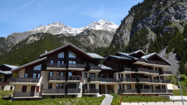 Un hotel a più piani con balconi, con le montagne innevate sullo sfondo.