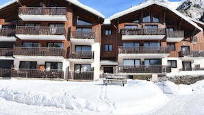 Un edificio in legno a più piani con balconi, immerso nella neve e circondato dalle montagne.