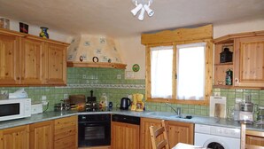 Eine Küche mit Holzschränken, einer Mikrowelle, einer Kaffeemaschine und einer Waschmaschine.