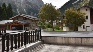 Un chalet de montagne avec une façade en bois, un espace de stationnement couvert et une vue sur une chaîne de montagnes.
