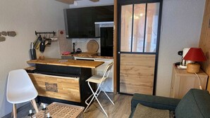Un espace de vie compact comprenant un coin cuisine, un coin repas et un coin salon.