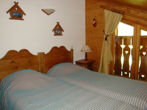Una stanza in legno con due letti, un comodino, una lampada e elementi decorativi alle pareti.