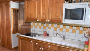 A kitchen with wooden cabinets, a white stove, and a tiled backsplash. - 4-room Duplex with balcony and parking in Pralognan, near slopes (Pralognan-la-Vanoise)