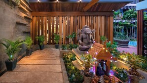 A serene indoor garden with a large elephant statue, wooden slats, and potted plants. - Cheata Residence (Siem Reap)
