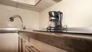 A kitchen with a modern coffee maker on the counter, a stainless steel faucet, and wooden cabinets. - Apartment Rubin (Belgrade)
