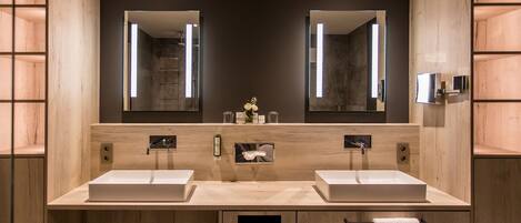 A modern bathroom with two sinks, large mirrors, and wooden cabinetry.