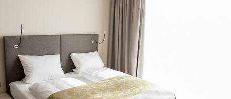Un dormitorio moderno con una cama grande, un cabecero gris y suelo de madera.