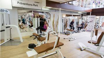 Una palestra con diverse attrezzature per esercizi, tra cui panche e macchinari per pesi, e un cartello per Dr. Wolff's Prevention Park.