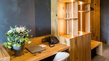 Un espace de bureau moderne avec un bureau en bois, un téléphone, une plante en pot et une chaise.
