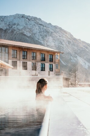 A spa area with a wooden building in the background and a mountainous landscape.