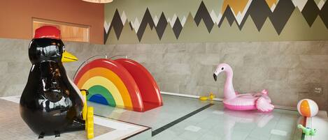 Zona de juegos infantiles con juguetes inflables, incluyendo un pato, un arcoíris y un cisne.