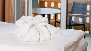 A hotel room with a bed, a window with a view of mountains, and a balcony with outdoor furniture. - aja Ruhpolding (Ruhpolding)