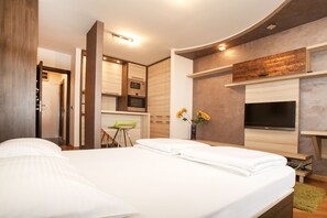 A modern bedroom with a large bed, a TV mounted on the wall, and a kitchenette in the background. - Apartment Retenzija (Belgrade)