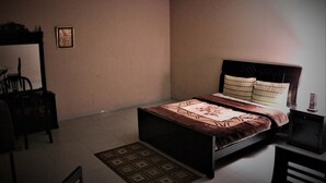 A bedroom with a bed, a desk, and a chair.
