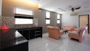 Un salon moderne comprenant un ensemble de canapés, un coin cuisine avec un plan de travail et un ventilateur de plafond.