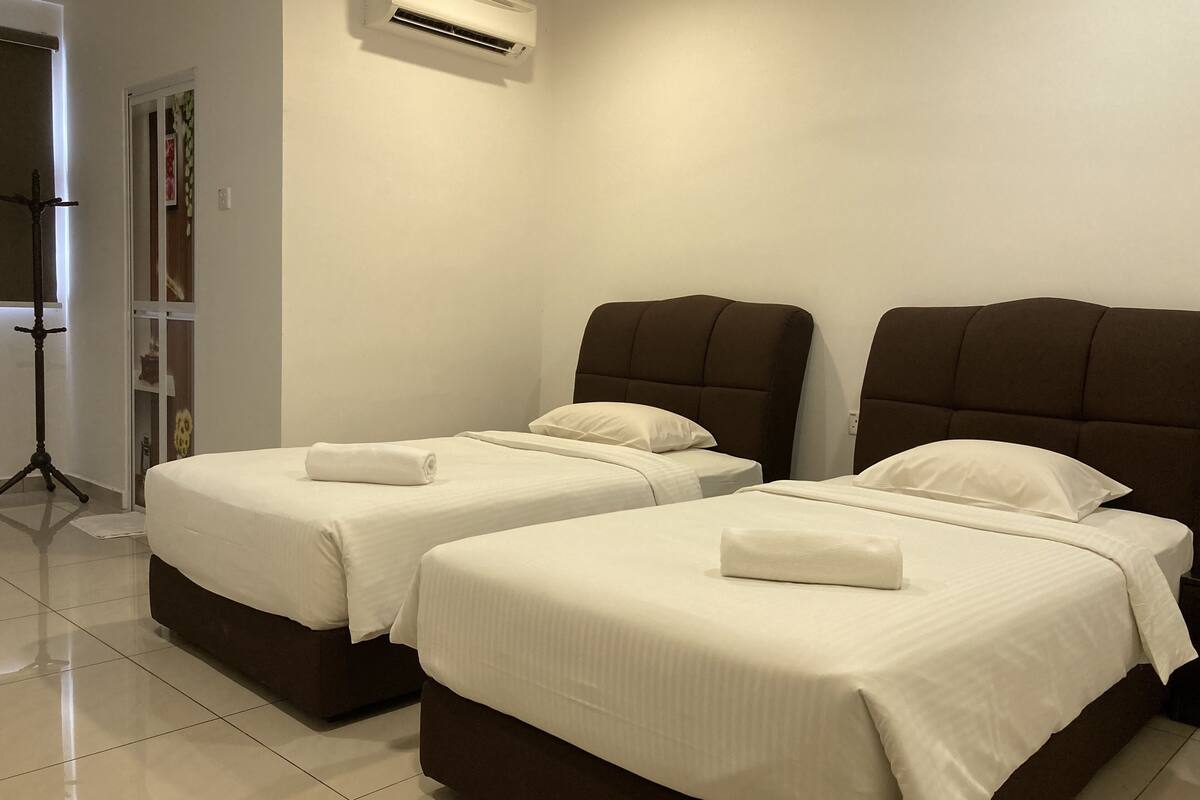 A hotel room with two beds, each with a brown headboard and white bedding.
