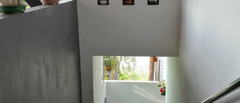 A staircase with a handrail, leading to a landing with a view of greenery outside.